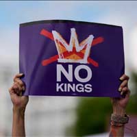 Person holding up a sign that reads, "NO KINGS".