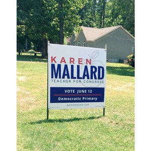 Campaign road sign for Karen Mallard, Teacher for Congress, on a grassy lawn with trees and a house in the background.