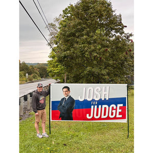 Person standing next to a road sign that says, 'Josh for Judge'.