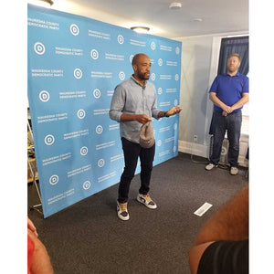 Man standing in front of a pop-up backdrop for the Waukesha County Democratic Party.